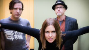 Image of Julia Hatfield and two band members against a green and yellow background.